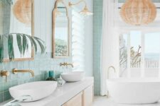 a bright and airy coastal bathroom with mint green tiles, a floating vanity, an oval tub, a woven pendant lamp and some lamps