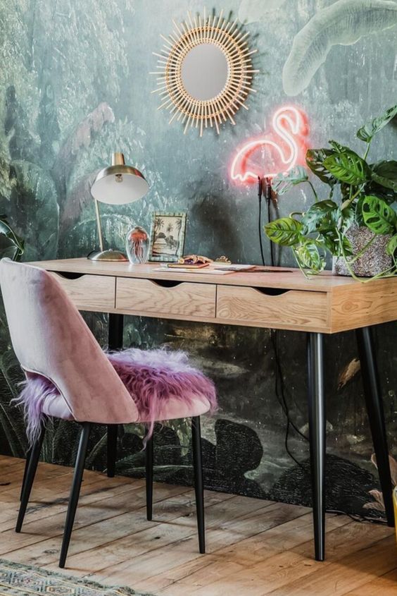 a bright and chic home office with a tropical wall mural, a lavender chair, a flamingo neon light, a sunburst mirror and potted plants