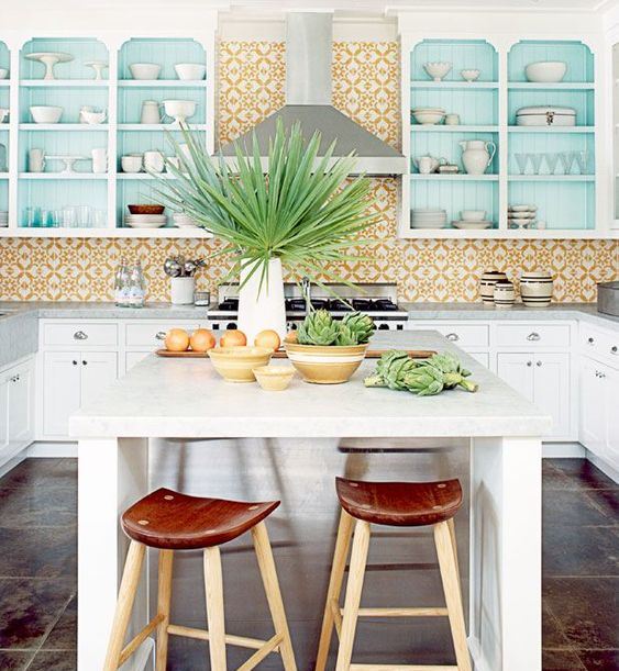 a bright and fun kitchen with a yellow tile backsplash, blue cabinets and a kitchen island with wooden stools