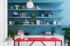 a bright blue contemporary home office with neutral storage units, floating shelves in blue and a hot red desk to contrast