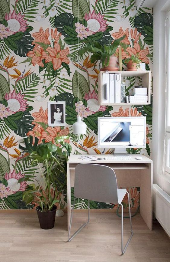 a bright home office nook with colorful tropical print wallpaper, minimal white furniture and potted greenery