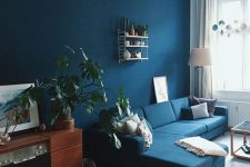 a bright living room with a navy accent wall and a sofa, wooden furniture, potted plants and geometric decor