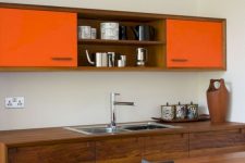 a bright modern kitchen with rich stained wooden cabinets and touches of bold orange is very spectacular