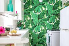 a bright tropical kitchen with a banana leaf wall and ceiling, white cabinets and bright tableware for fun