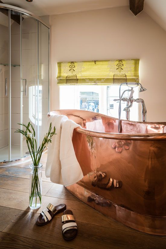 a chic attic bathroom with a shower space and a copper bathtub is a cool and bold eclectic space