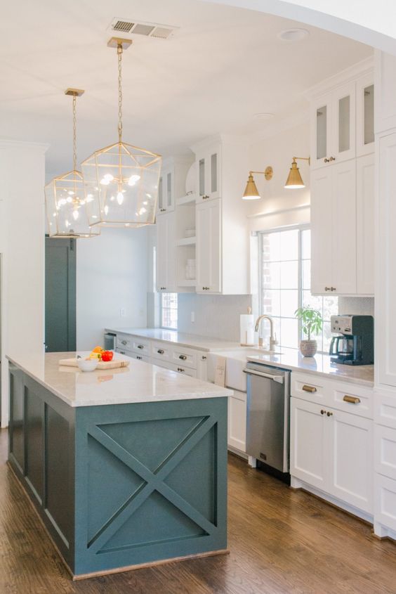 a chic farmhouse coastal kitchen with white cabinets, a teal kitchen island, gold pendant lamps and sconces