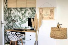 a chic tropical home office nook with neutral furniture, a tropical leaf wall, a woven lamp and pampas grass