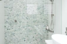 a coastal bathroom with large format tiles, light green and grey fish scale tiles in the shower, a timber vanity