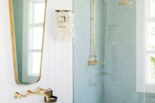 a coastal bathroom with mint blue tiles and white marble ones, a white floating vanity, a mirror and gold fixtures
