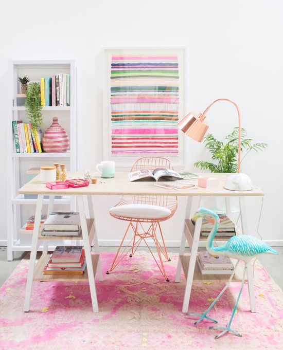 a colorful and cheerful home office with bright printed rug, a striped artwork and pink accessories plus a turquoise flamingo