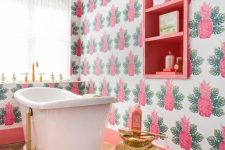 a colorful tropical bathroom with pink pineapple wallpaper, a pink built-in shelf and touches of gold here and there