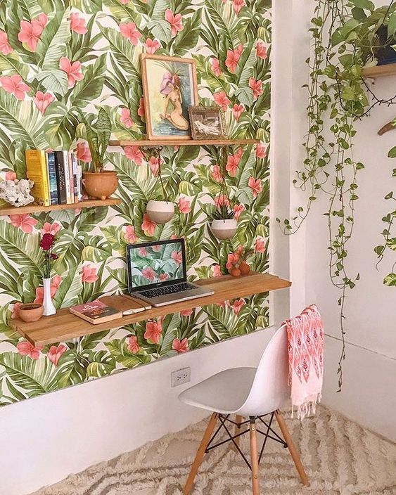 a colorful tropical home office nook with a tropical accent wall, a floating desk and shelves and potted plants