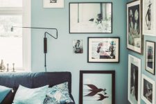 a creative living room with grey blue walls, a navy sofa, blue printed pillows and a gallery wall in the corner