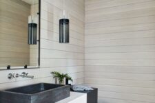 a creative modern beach bathroom with shiplap walls, a floating vanity with a black sink, a mirror and a pendant lamp