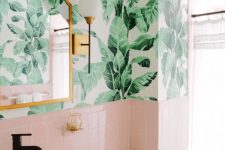 a cute tropical bathroom with banana leaf wallpaper, pink tiles, a copper mirror and a white bowl sink