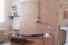 a delicate eclectic bathroom in peachy pink and blush, with a copper bathtub and a vintage chandelier is very welcoming
