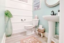 a lovely beach bathroom with a white shiplap wall, an aqua accent wall, a free-standing sink, a round mirror and cool decor