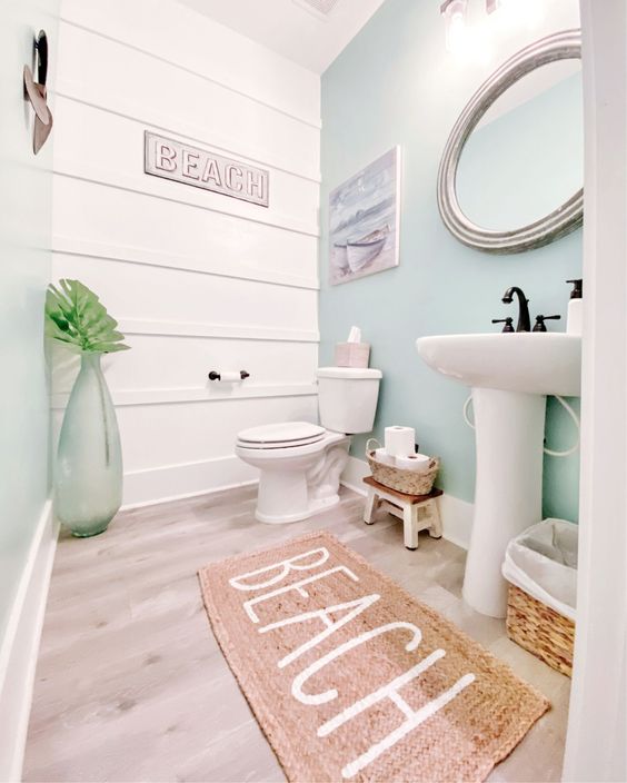 a lovely beach bathroom with a white shiplap wall, an aqua accent wall, a free-standing sink, a round mirror and cool decor