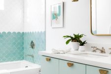 a lovely beach bathroom with mint green touches, fish scale tiles in the shower and a mint floating vanity and brass touches