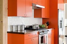 a matte orange kitchen with a white tile backsplash, a bright rug and wooden countertops is bright and cheerful