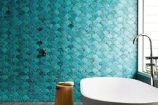 a minimalist bathroom inspired by the sea, with turquoise fish scale tiles and an oval bathtub