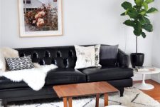 a modern Scandinavian living room with a black leather sofa, a white leather ottoman and other black and white decor for a cohesive look