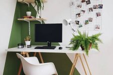 a modern home office with a color block green and white wall, white furniture, a grid and potted plants