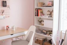 a modern home office with light pink walls, neutral furniture, a fluffy white lamp and copper touches