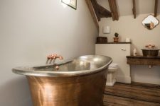 a modern rustic bathroom with wooden beams and furniture and a copper bathtub plus fxitures for a wow effect