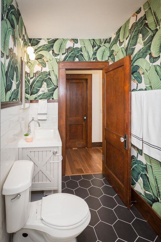 a modern tropical bathroom with banana leaf wallpaper, white appliances and a grey vanity is very lovely