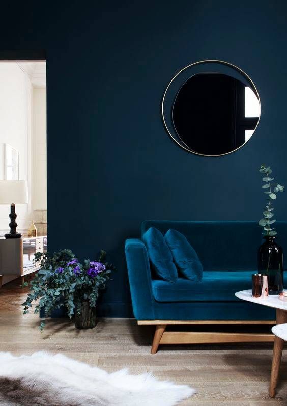 a monochromatic navy living room with navy walls and a sofa, white and wood tables and a faux fur rug