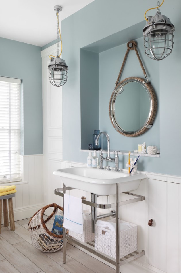 a nautical bathroom with a slate blue half wall, a vintage sink, vintage pendant lamps and a wooden floor