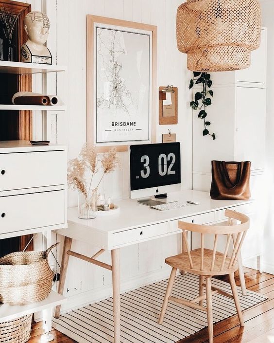 a neutral boho home office with a chic desk, a wooden chair, a woven lamp and a gallery wall