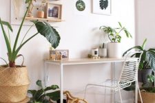 a neutral tropical boho home office with white furniture, a pegboard with a dreamcatcher and various decor plus potted plants
