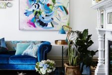 a neutral vintage-inspired living room infused with color – a bold blue sofa and rug, a colorful artwork and some more blue touches