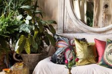 a neutral yet moody living room with neutral walls, a neutral sofa, a vintage suitcase as a coffee table and potted plants plus a vintage mirror
