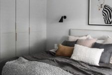 a peaceful contemporary bedroom with dove grey walls and a storage unit, grey bedding with touches of blush and a statement artwork