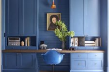 a pure blue home office with built-in storage units, open and closed ones, a floating desk and a blue chair is a statement in itself