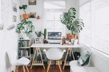a pure white small home office with a trestle desk, white furniture, potted plants and a gallery wall is very welcoming