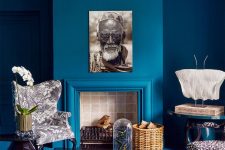 a refined and catchy living room with classic blue walls, a matching sofa and a side table plus statement prints