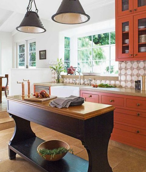 a refined burnt orange kitchen with an aubergine kitchen island and black pendant lamps plus touches of brass