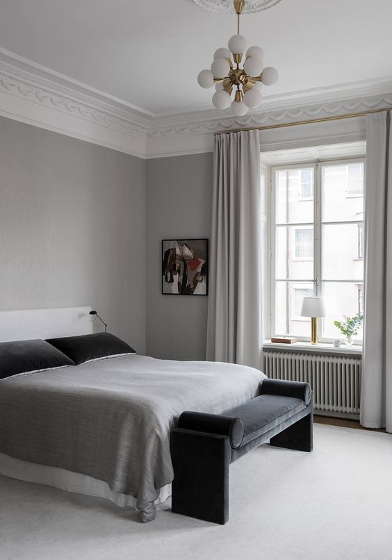 a refined minimal bedroom in light grey, with textiles in various shades of grey and black elements for a contrast