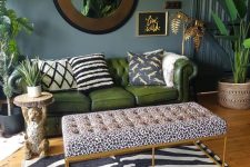 a refined tropical living room with grey walls, a green leather sofa, a leopard ottoman and zebra rug plus potted plants