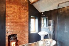 a refined vintage bathroom with black walls, a hearth, a crystal chandelier, a copper tub and vintage fixtures