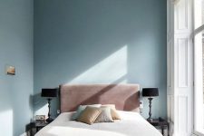 a refined yet minimal bedroom with blue walls, a ceiling with molding and a glazed wall, a pink bed and an upholstered bench