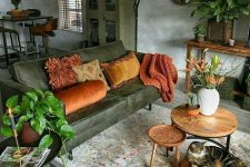 a relaxed boho space with a green leather couch, wooden furniture and potted greenery is welcoming and simple