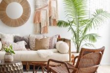 a relaxed boho tropical living room done in neutrals, with rattan furniture, woven and fringe wall hangings and a statement plant