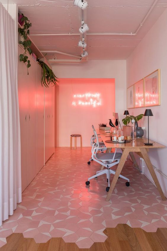 a shared millenial pink home office with a pink accent wall with neon, pink and white hex tiles and neutral furniture