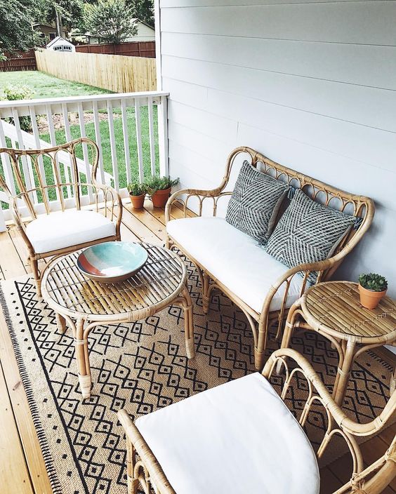 a simple and chic coastal porch with rattan furniture, neutral textiles and a boho printed rug is lovely