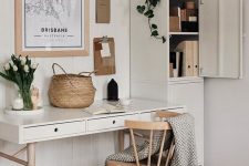 a small neutral home office with modern furniture, potted plants, a gallery wall and a basket